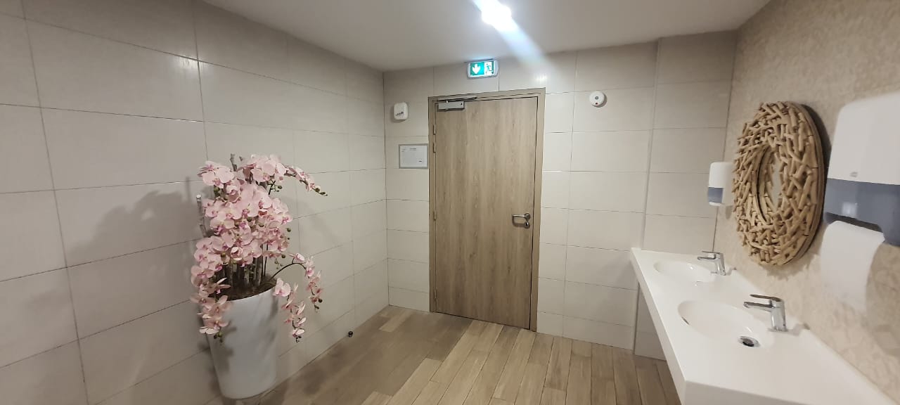 Sanitaires avec double vasque et diffuseur mural près de la porte