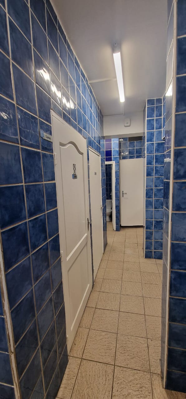 Couloir de sanitaires au carrelage bleu avec diffuseur en hauteur