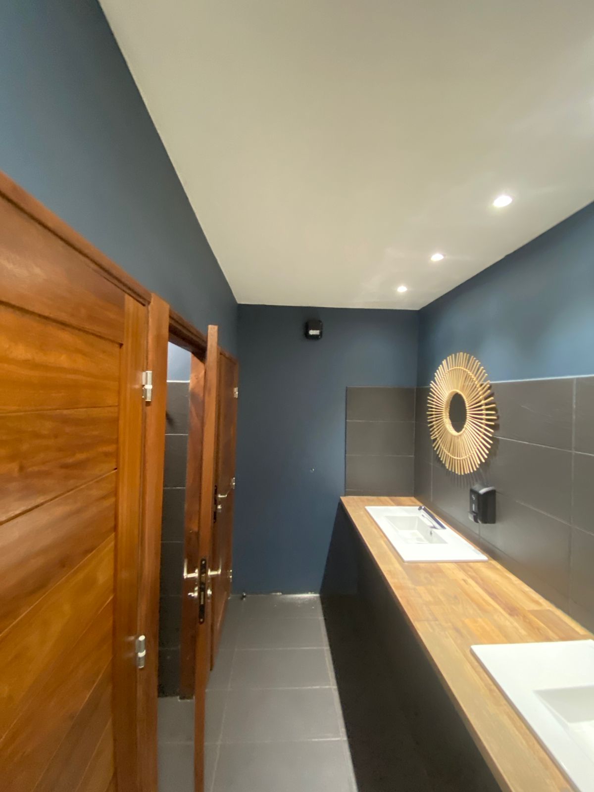 Lavabos sur un plan en bois et diffuseur installé sur le mur bleu
