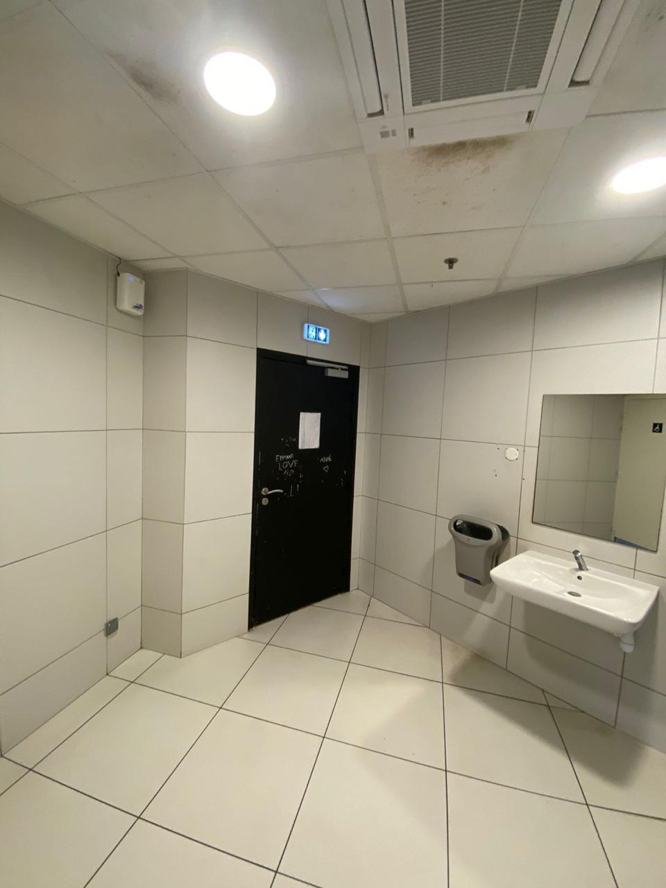 Diffuseur blanc fixé en hauteur dans des sanitaires carrelés