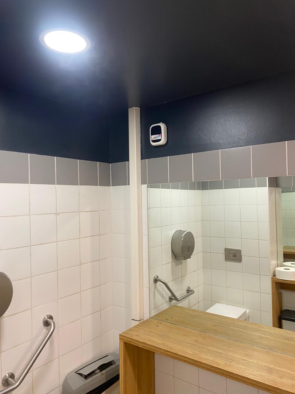 Diffuseur mural dans des sanitaires aux murs blancs et bleu foncé